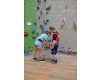 Kletterwand: Mädchen hilft Bub beim Anlegen des Klettergurts in der Kletterhalle